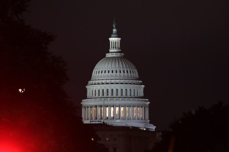 The U.S. Capitol building at night with a red light in the corner.