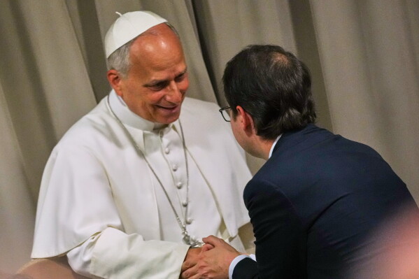 Pope Leo XIV, left, greets Anthropic co-founder Christopher Olah during the presentation of the Pope's first encyclical