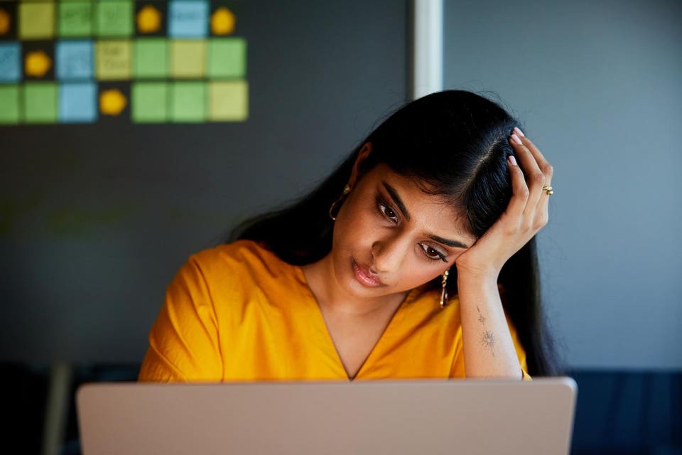 Young businesswoman looking stressed while working on laptop in an office