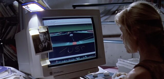 A still from Jurassic Park, showing a young woman sitting at an SGI workstation, with the 3D file system navigator visible on the screen.