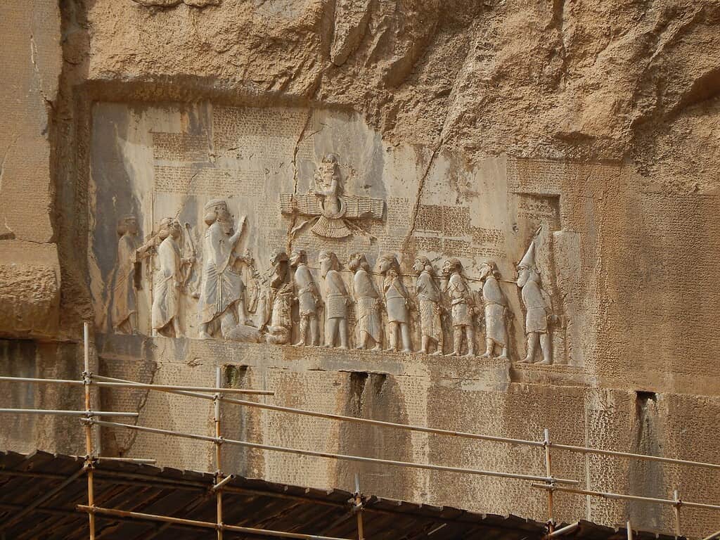 Ancient stone relief depicting a procession of figures with a musician and a leader